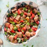 Panzanella in an oval bowl with basil scattered around