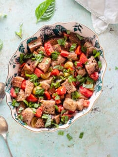 Panzanella in an oval bowl with basil scattered around