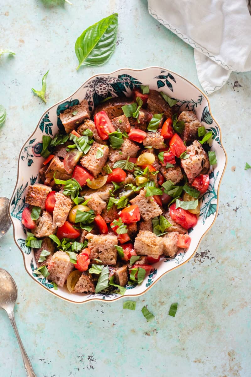 Panzanella in an oval bowl with basil scattered around