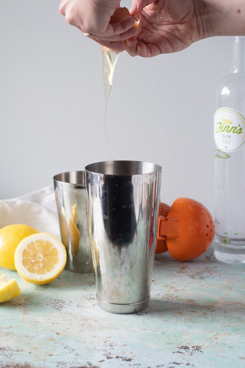 Hands separating an egg into cocktail shaker