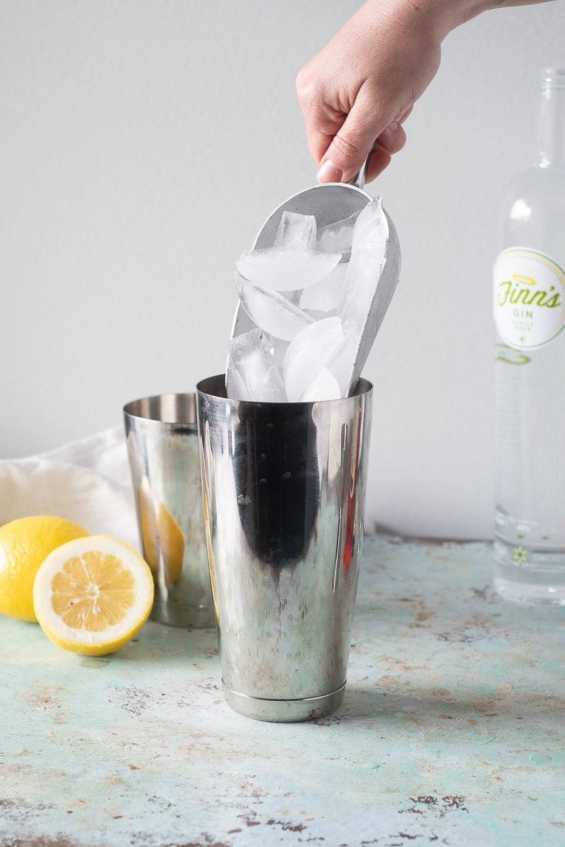 Hand adding ice to cocktail shaker