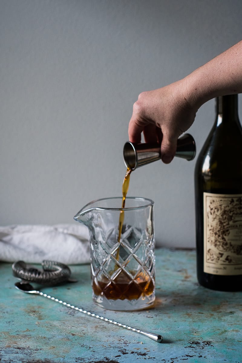 Hand pouring Old Tom Gin into a mixing glass