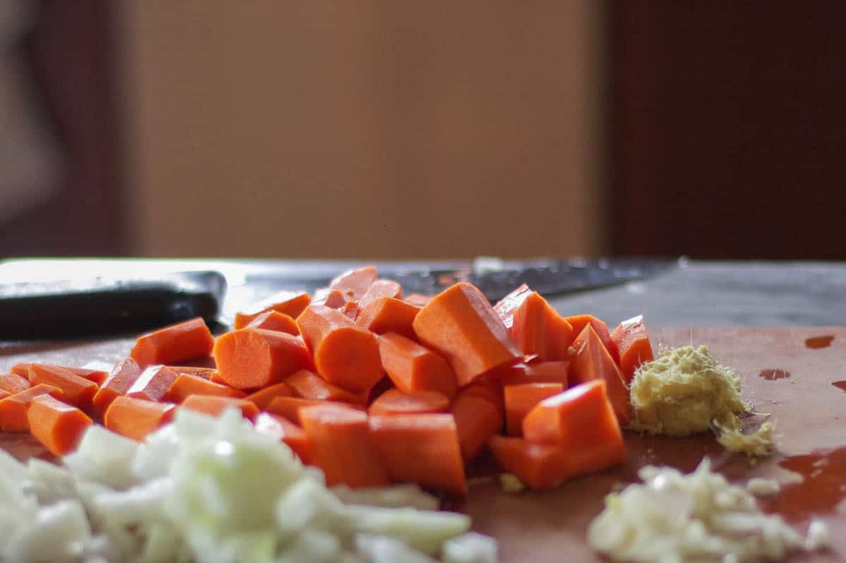 Chopped carrots, onion, and ginger on a cutting board