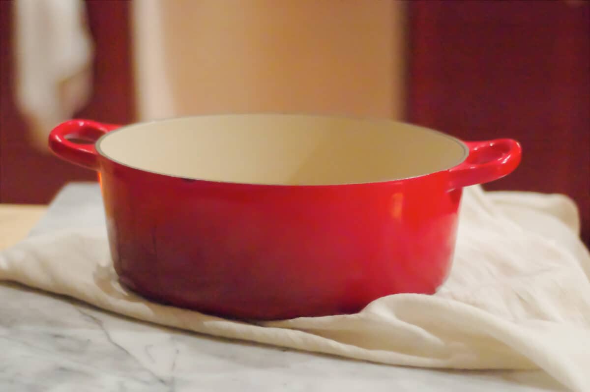 A red Dutch oven on a kitchen towel