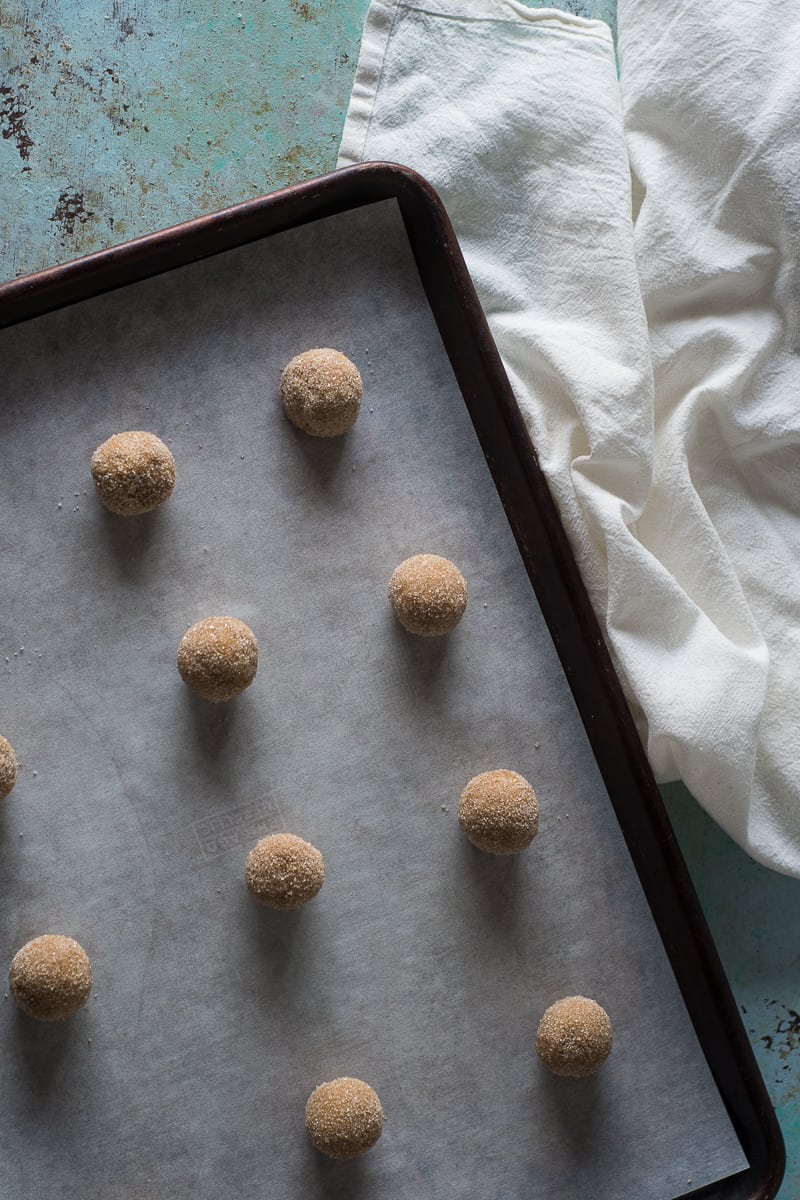 Balls of citrus molasses spice cookie dough on a sheet pan waiting to go into the oven