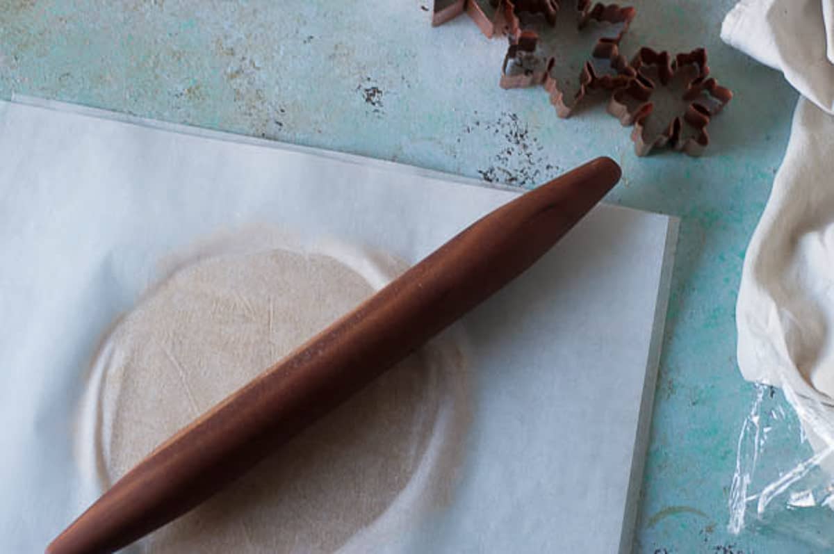 Orange Cardamom dough being rolled out between parchment paper