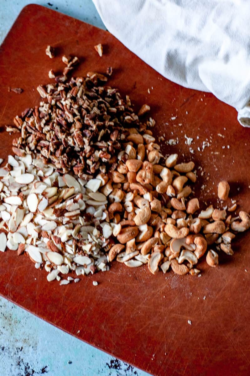 Chopped pecans, cashews, and almonds on a cutting board