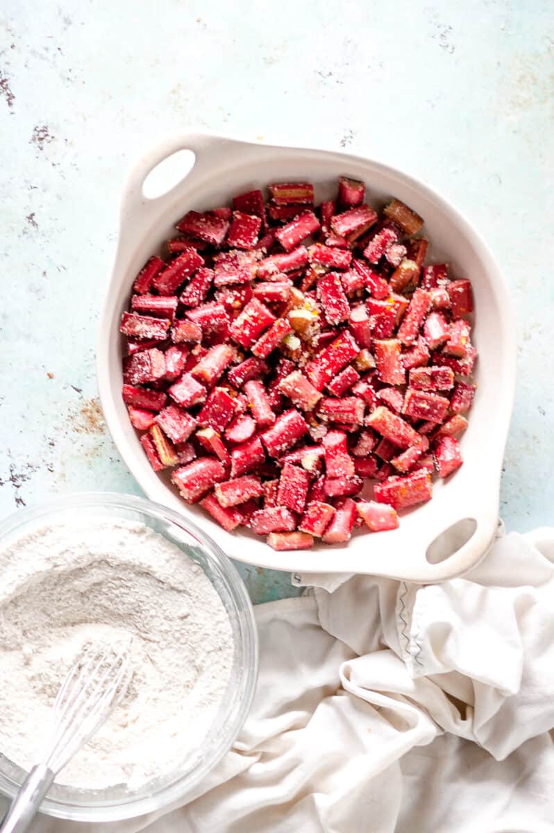 Sliced rhubarb tossed with sugar in a baking dish