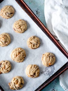 Chocolate butterscotch chip cookies on a parchment lined sheet pan