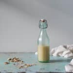 Orgeat (almond syrup) in a bottle with scattered almonds in the background