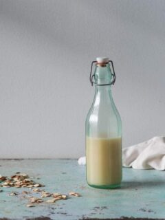 Orgeat (almond syrup) in a bottle with scattered almonds in the background