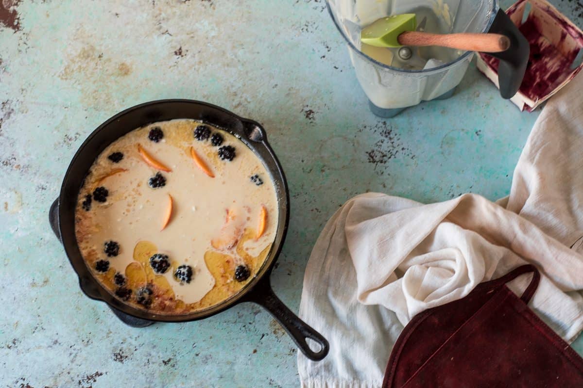 Batter Poured over peaches and blackberries in a cast iron skillet