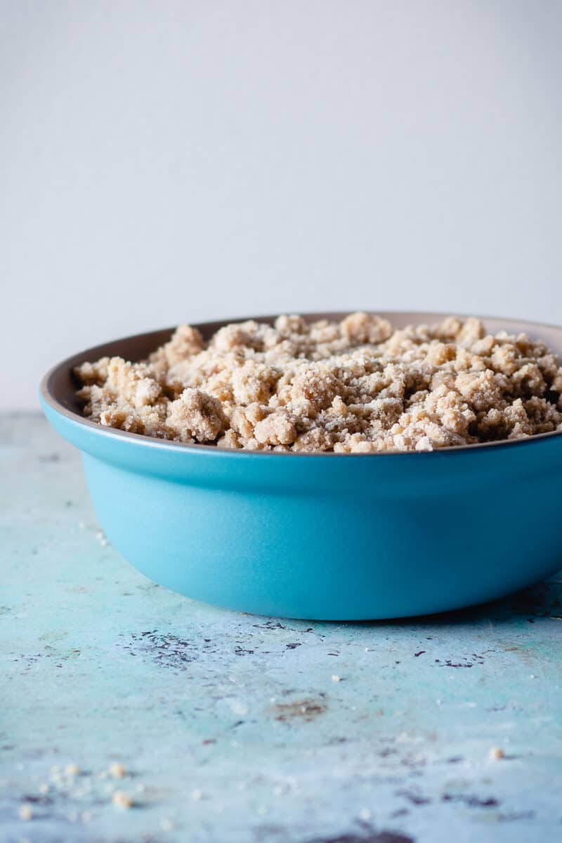 Assembled raspberry plum crisp in a blue baking dish waiting to go into the oven