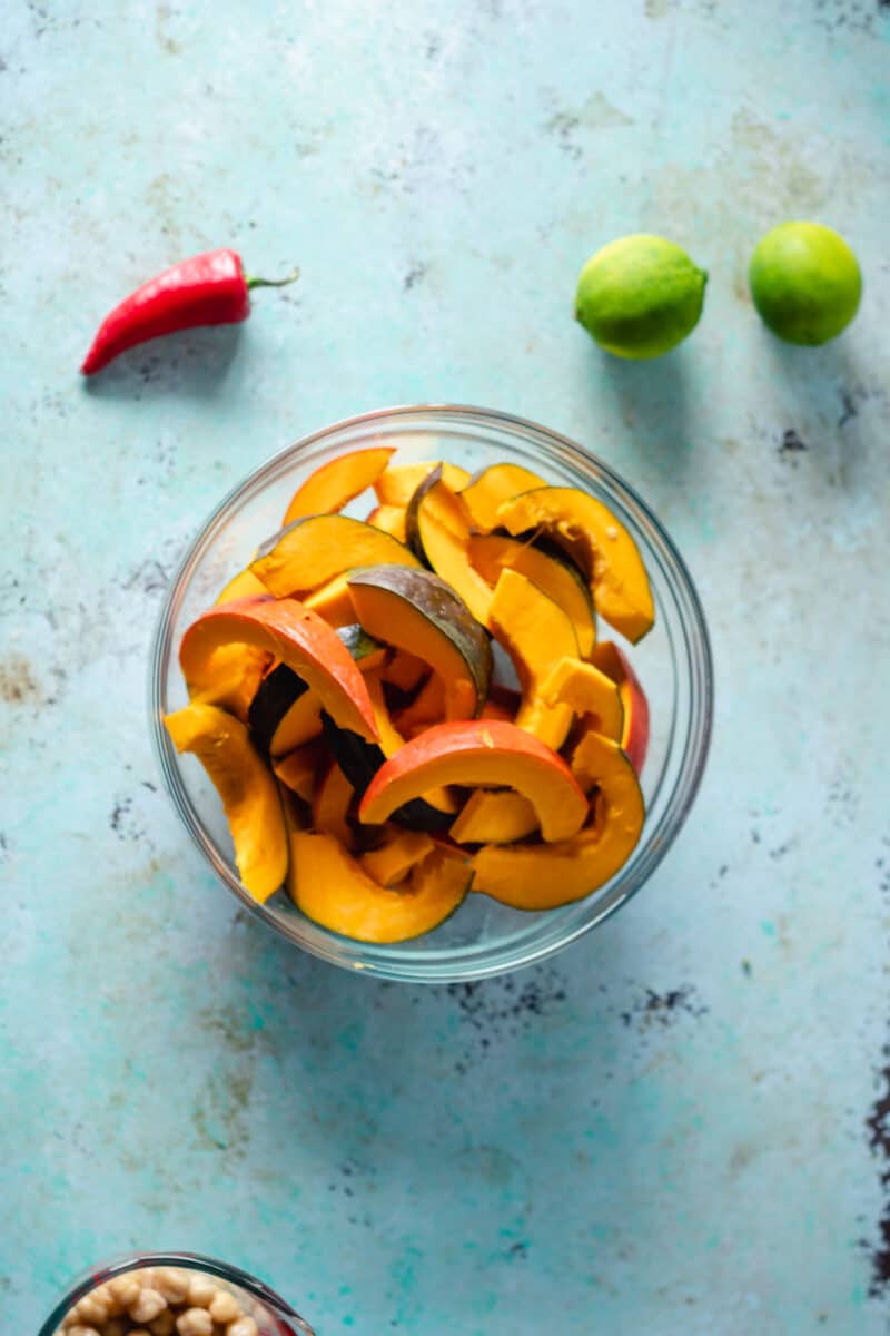 Sliced squash in a bowl with limes and a fresno chile nearby