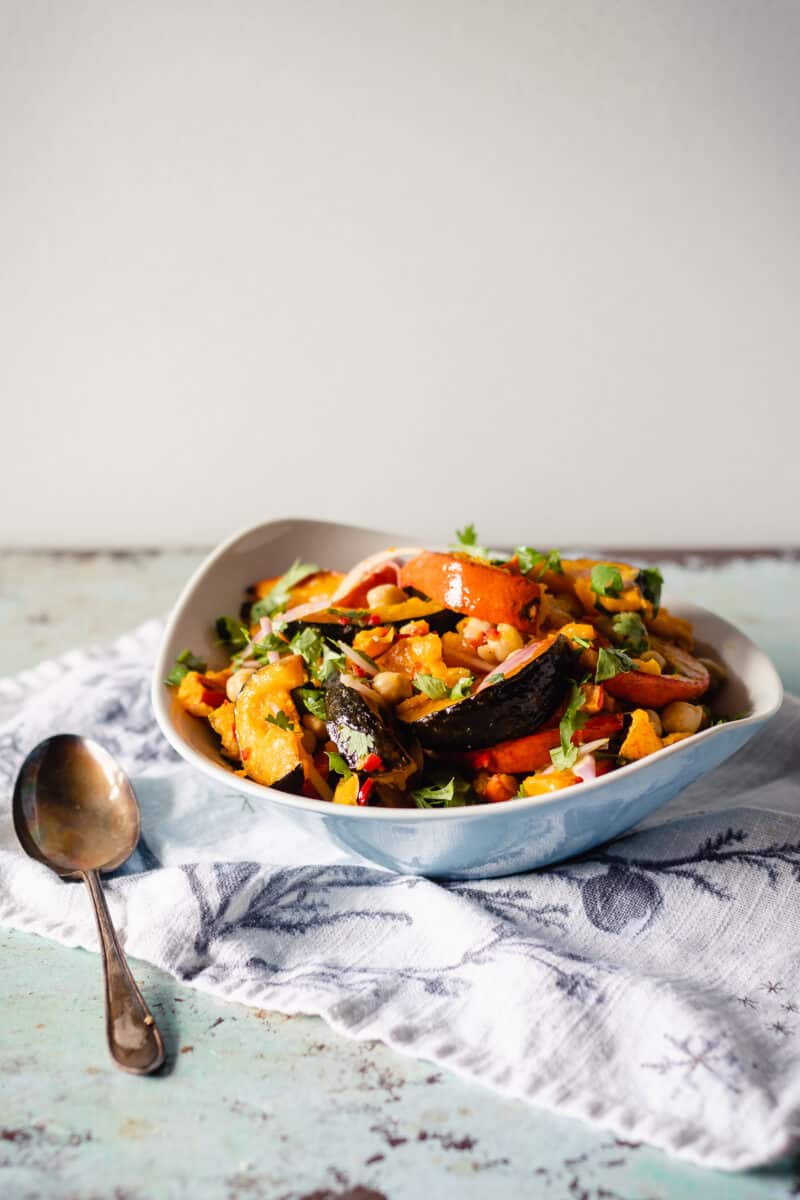 Chile-lime squash and chickpea salad in a blue bowl with a spoon and towel