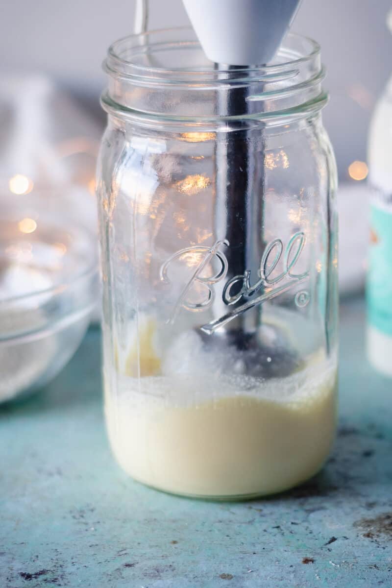 Immersion blender mixing eggnog in a mason jar