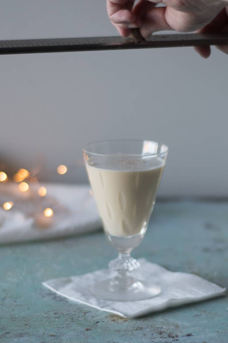 Grating nutmeg over a glass of eggnog