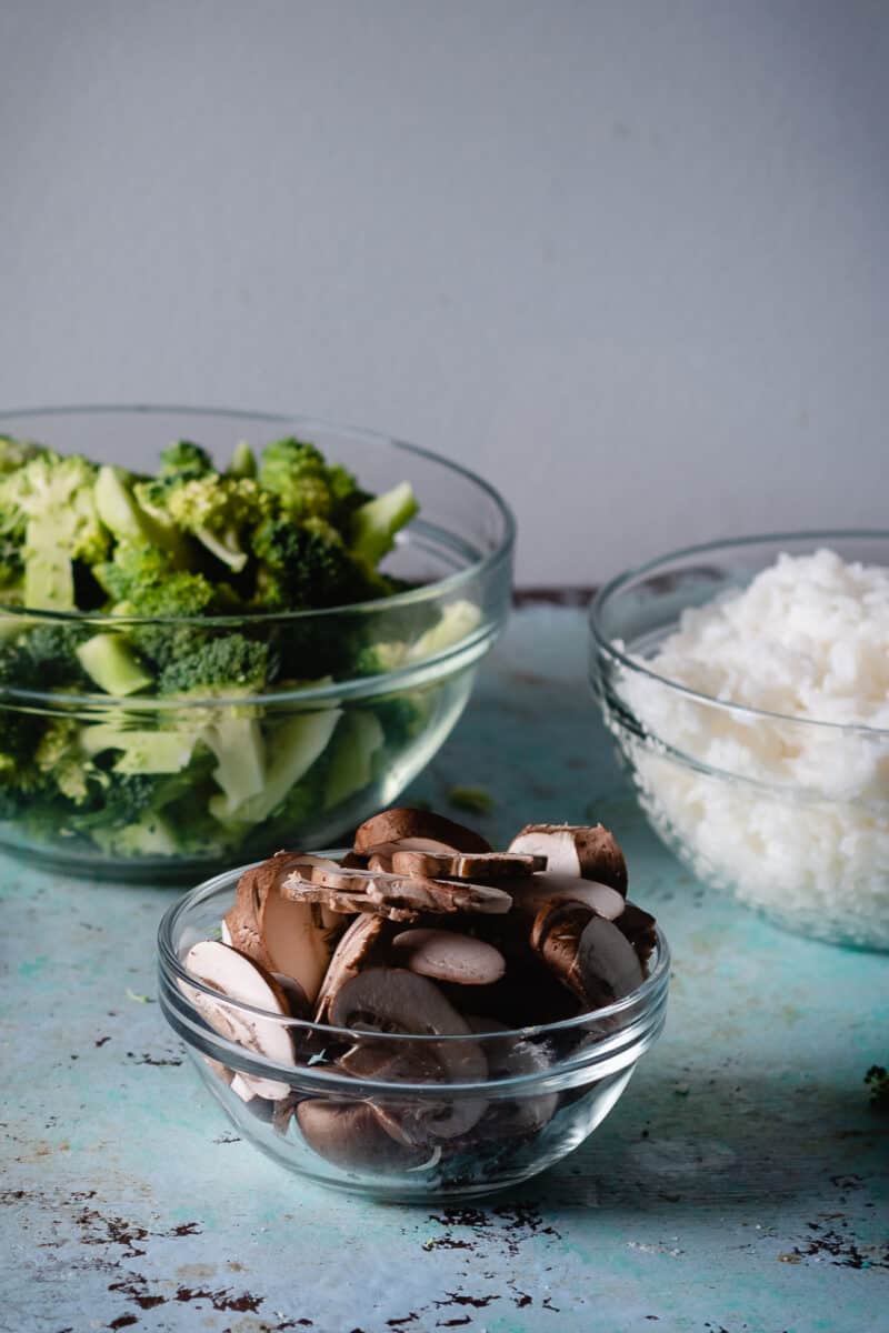 Chopped broccoli, sliced mushrooms, and steam rice in bowls