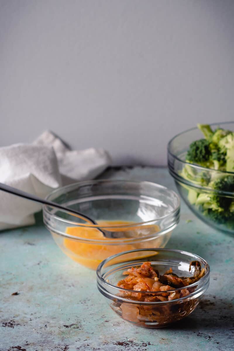 Beaten eggs in a bowl with kimchi in another bowl