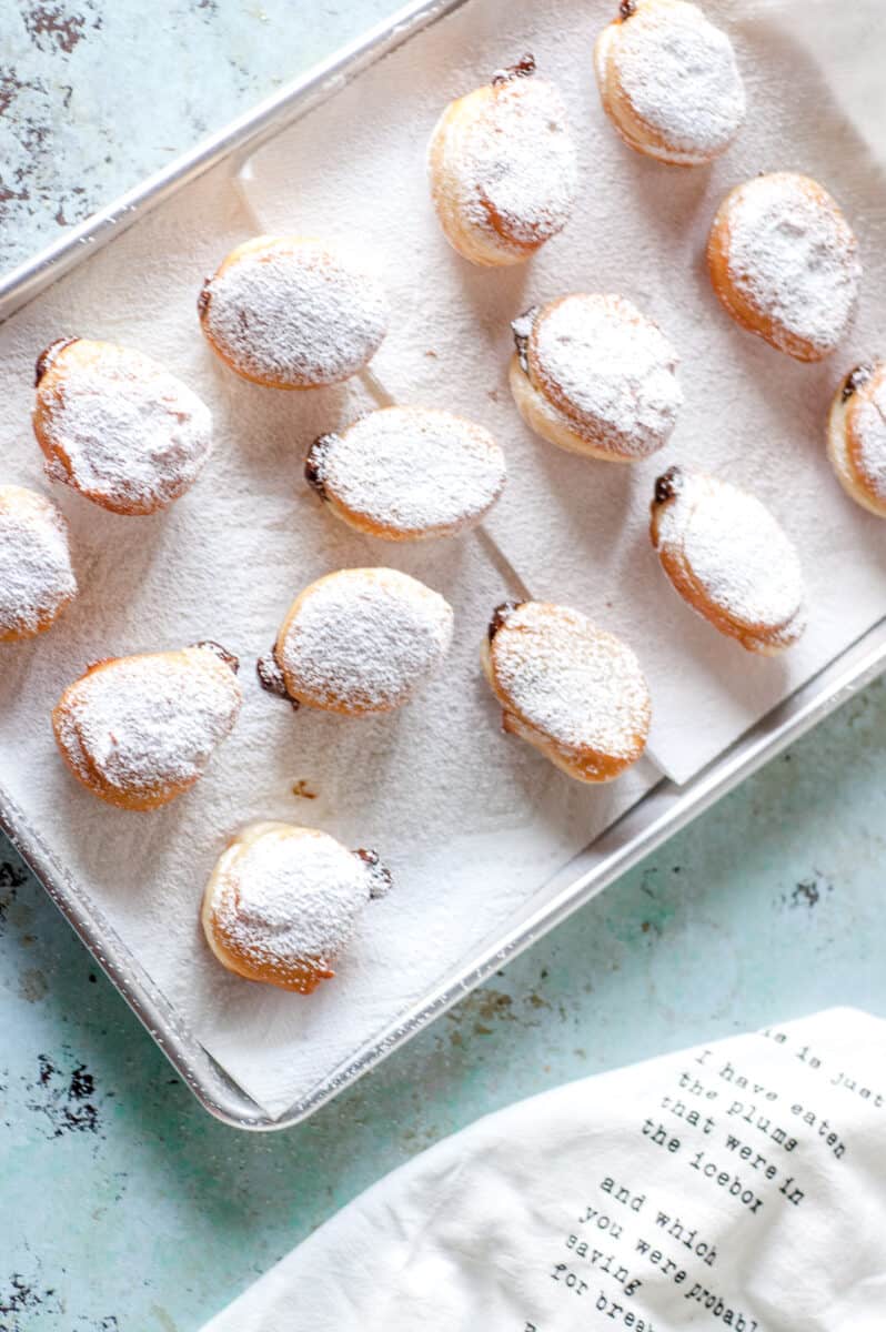 Paczki on a paper towels on a sheet pan