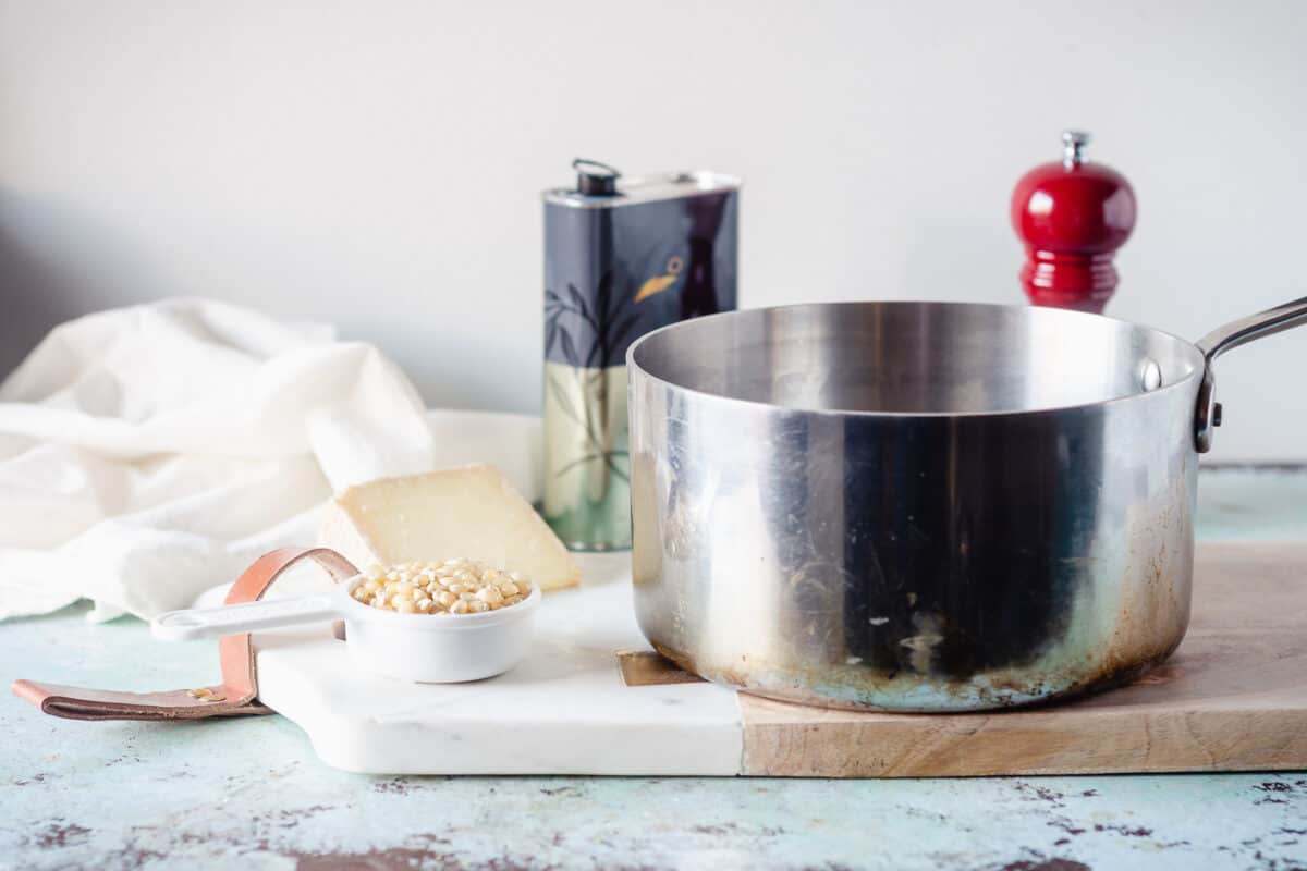 A saucepan next to unpopped popcorn