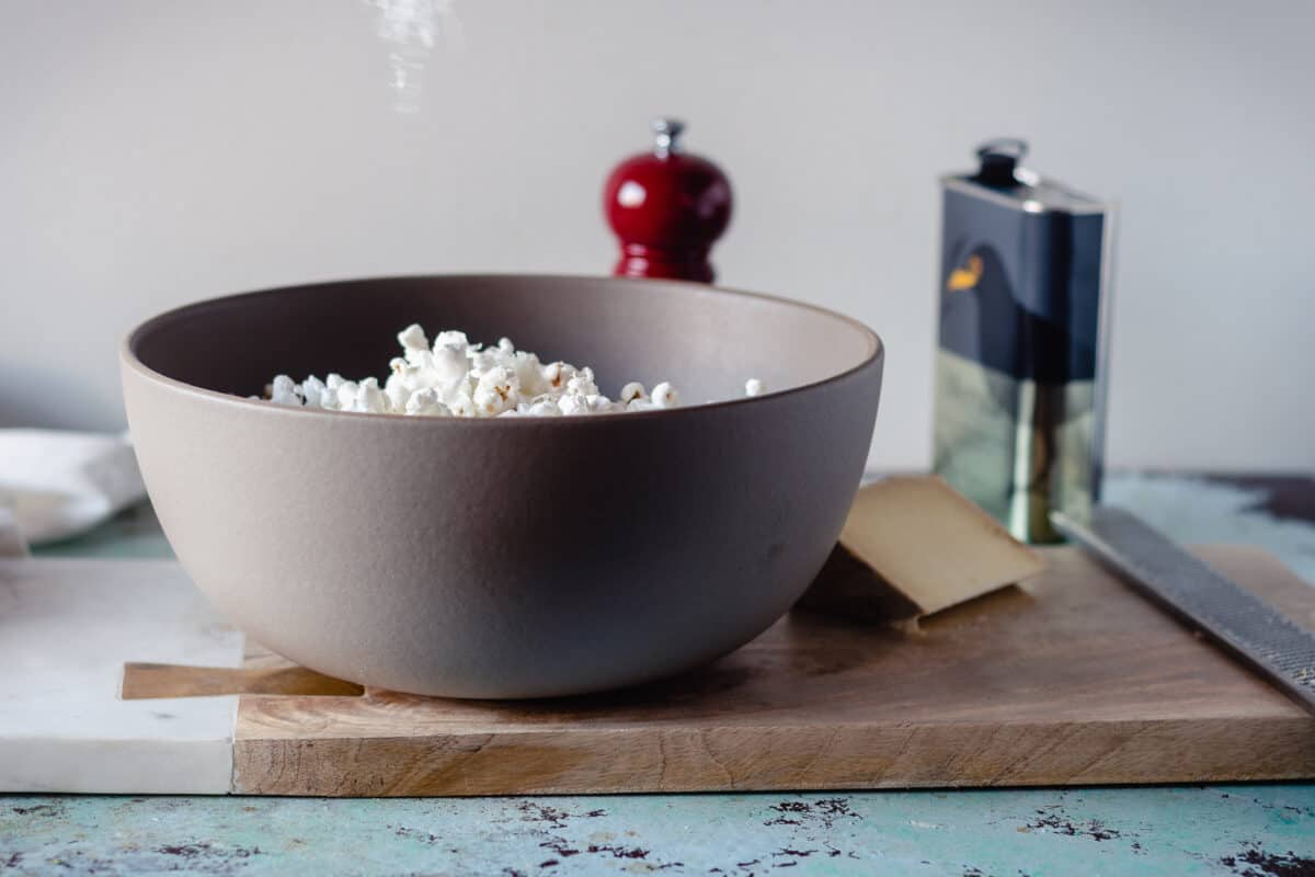 Shredded pecorino cheese being sprinkled over popcorn