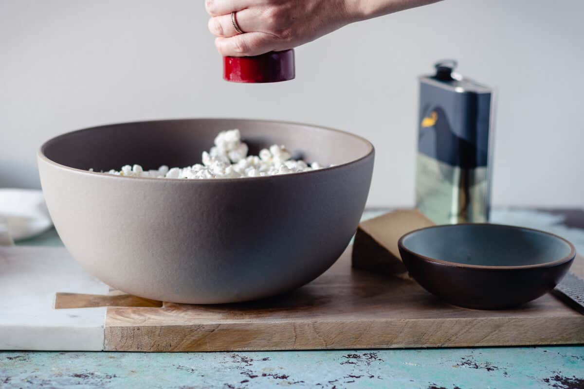 Pepper grinder over a bowl of popcorn