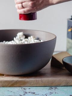 Pepper grinder over a bowl of popcorn