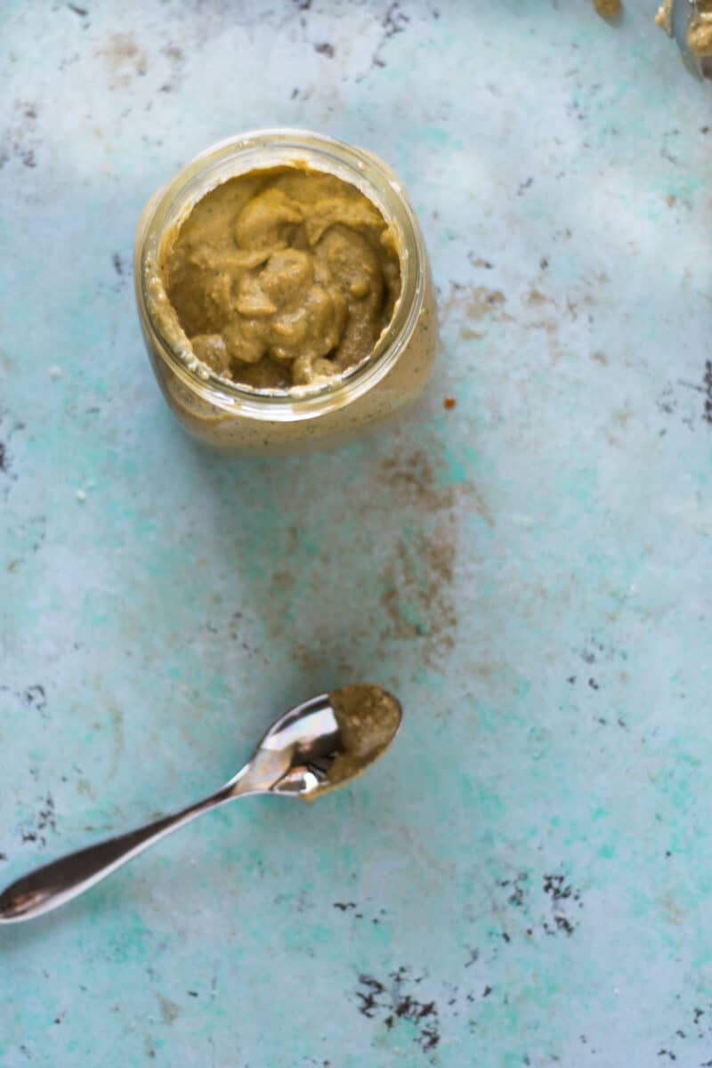 A jar of garlicky cashew sauce with a spoon next to it