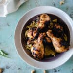 Grilled chicken legs on a plate slathered with garlicky cashew sauce