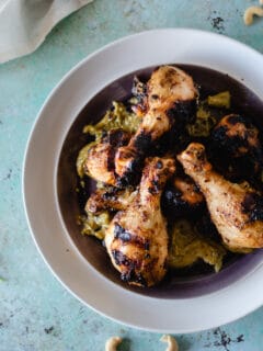 Grilled chicken legs on a plate slathered with garlicky cashew sauce