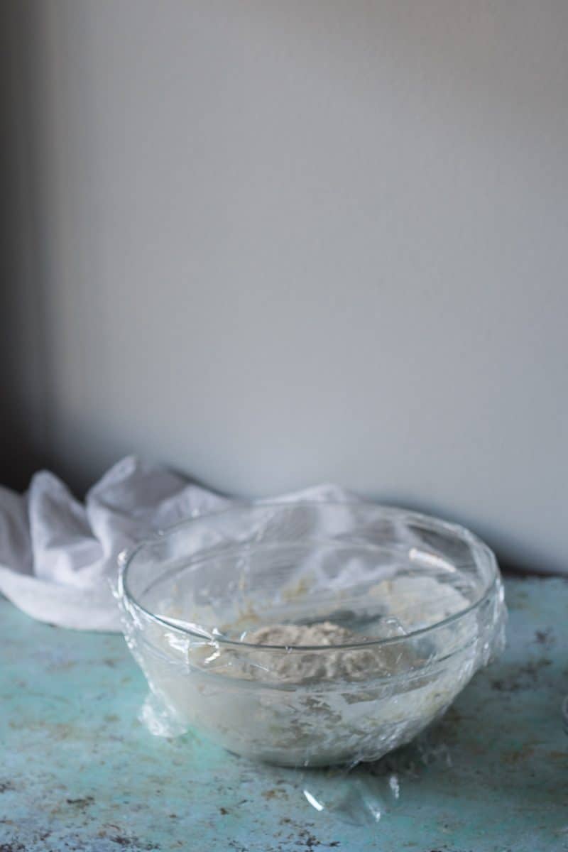 Pizza dough covered with plastic wrap for proofing