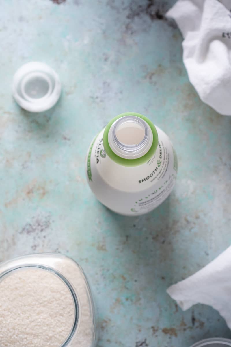 Overhead view of open almond milk bottle and canister of sugar