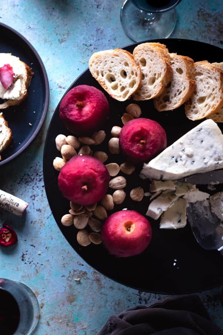 Cranberry Lapsang Poached Apples on a plate with cheese, almonds, and toast