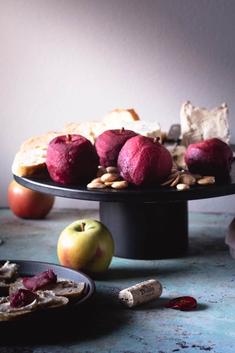 Cranberry Lapsang Poached Apples on a black stand with cheese and almonds