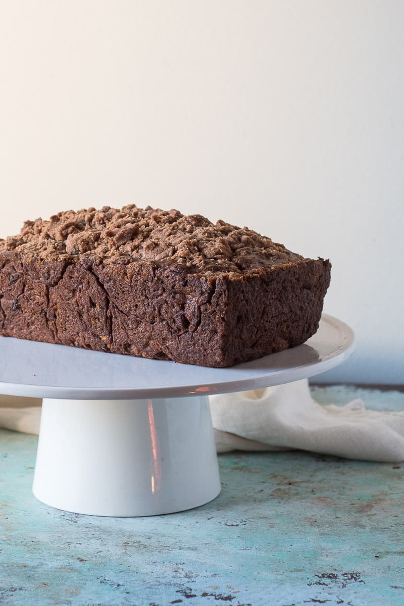 Streusel-topped Banana Bread with Chocolate and Pecans on a cake stand, side view