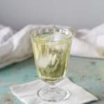 Clarified English Milk Punch in a glass with ice, vertical orientation