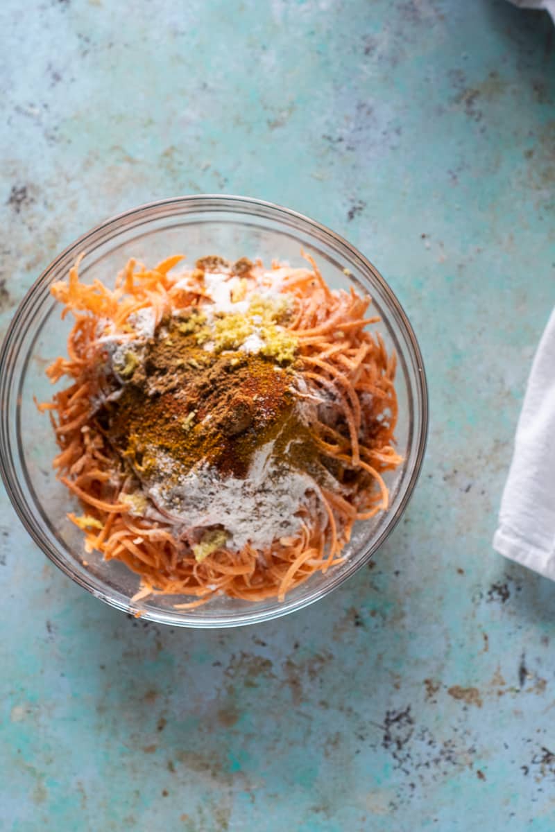 Shredded sweet potatoes, flour, and spices in a bowl