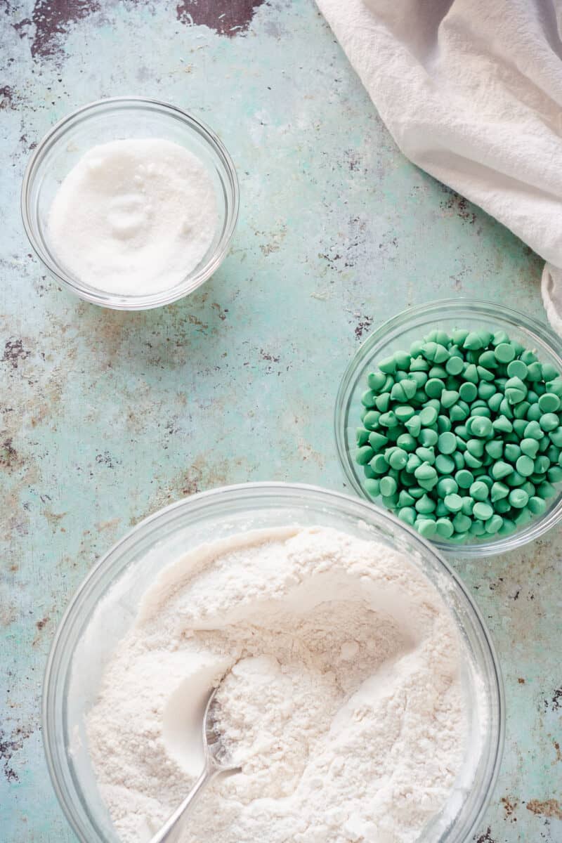 Flour mixture, green mint chips, and sugar in glass mixing bowls