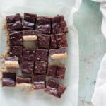 Sliced almond shortbread brownies with a few turned sideways on a piece of parchment paper