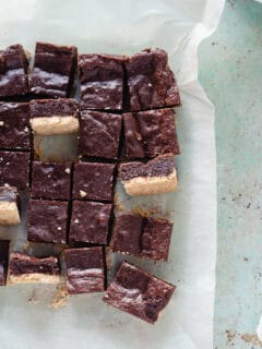 Sliced almond shortbread brownies with a few turned sideways on a piece of parchment paper