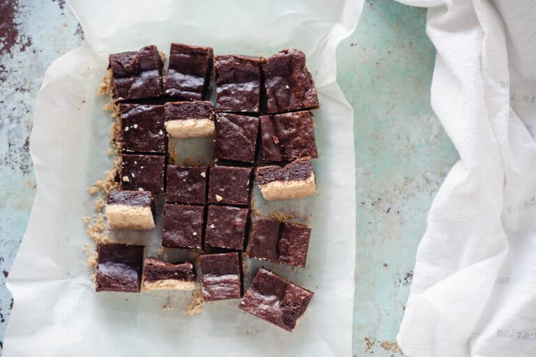 Sliced almond shortbread brownies with a few turned sideways on a piece of parchment paper