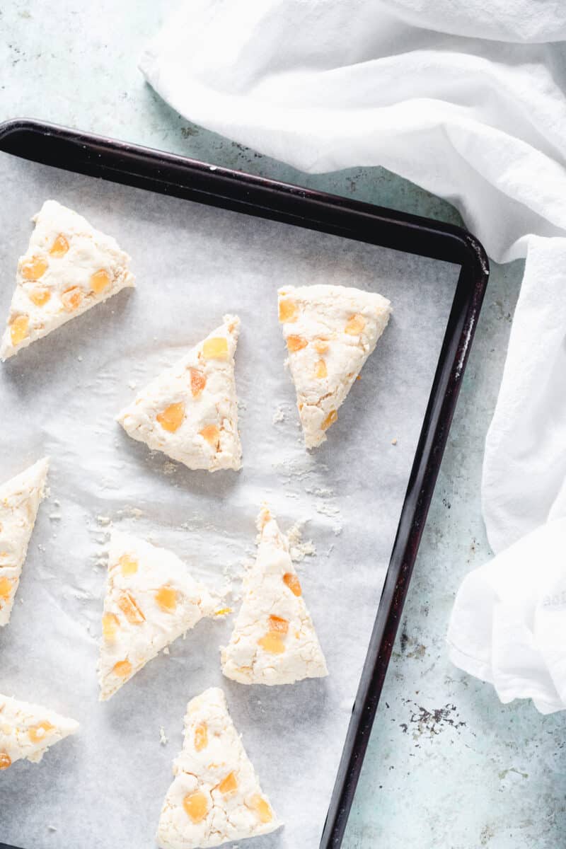 Unbaked orange ginger scones on a parchment-lined baking sheet