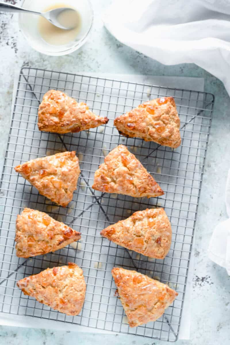 Orange ginger scones on a cooling rack with a bowl of creme fraiche icing alongside