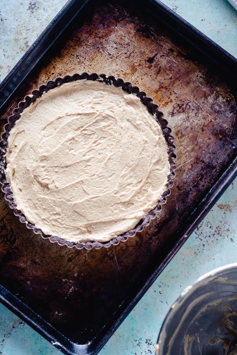 Peanut butter mousse spread in a chocolate tart shell on a sheet pan