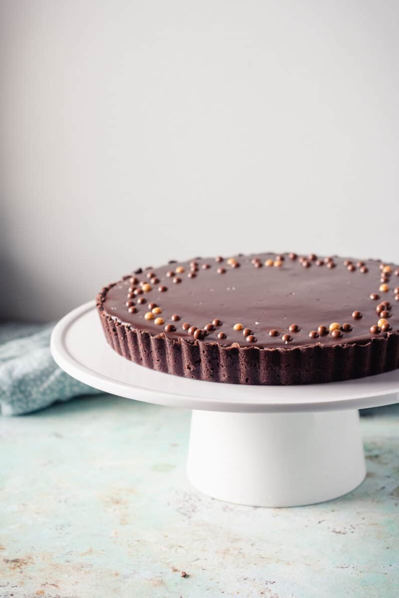 Chocolate peanut butter tart on a white cake stand