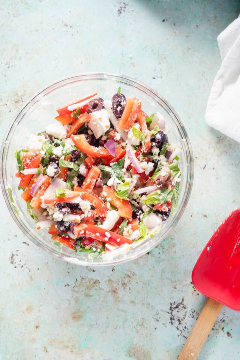 Feta, olive, and red pepper mixture in a glass mixing bowl