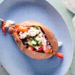 Baked Sweet Potato with marinated feta on a blue plate