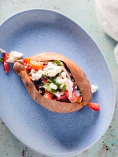 Baked Sweet Potato with marinated feta on a blue plate