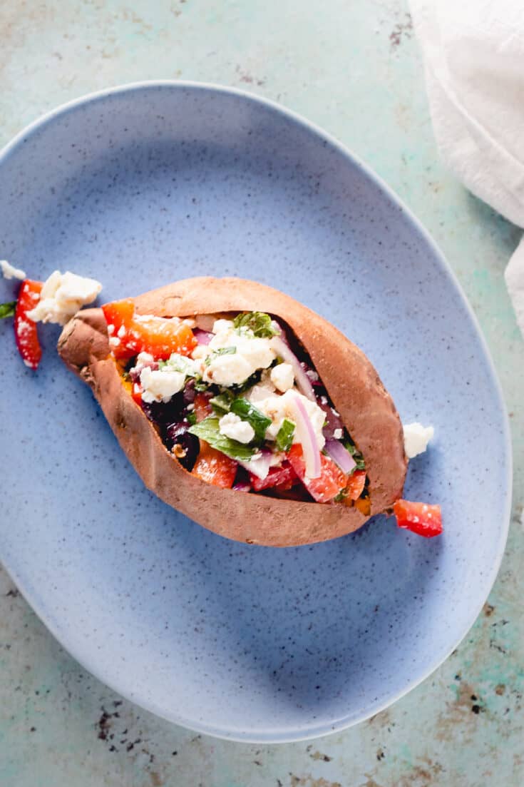 Baked Sweet Potato with marinated feta on a blue plate